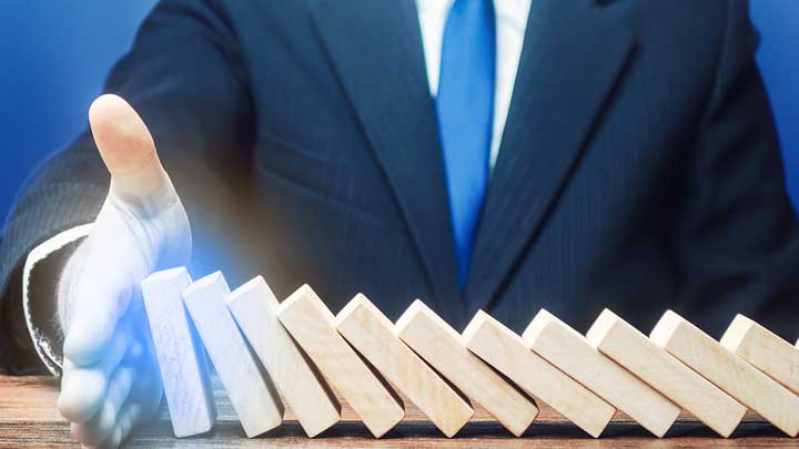 Mann stoppt fallende Dominosteine im Risikomanagement